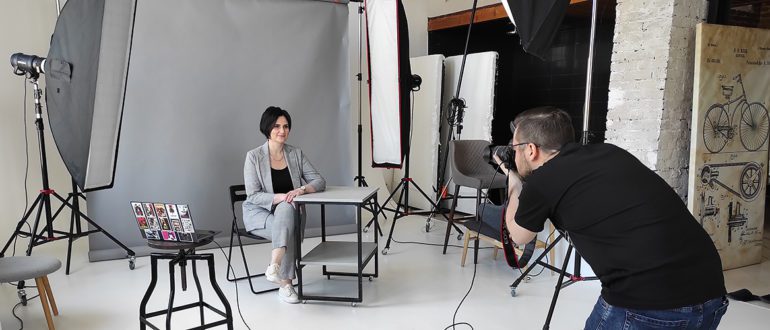 фотограф снимает деловой портрет женщины в студии